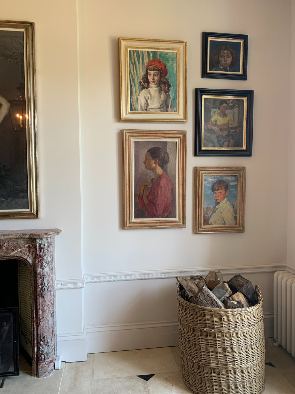 a collection of vibrant and textured portrait paintings beside a wicker log basket