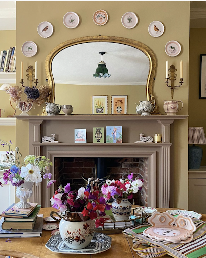 A tonal fireplace layered with ceramic pieces including a display of handmade decorative plates hung above