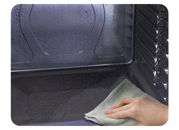 Shows a person easily wiping away a small amount of residue after the oven has been cleaned by the Steam Cleaning system.