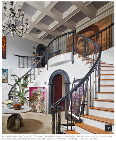 Large foyer with sweeping staircase, large bird of paradise staged between two brightly coloured paintings.