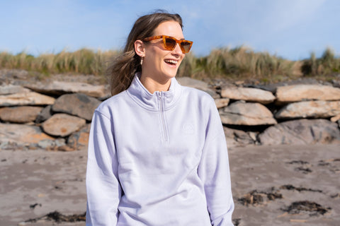 Girl smiling on beach wearing sunglasses and Outwest 1/4 zip