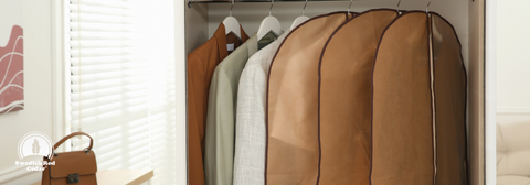 A closet with some suits in garment bags.