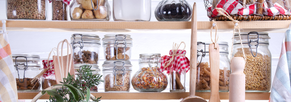 Shelfs filled with glass jars containing various foods.