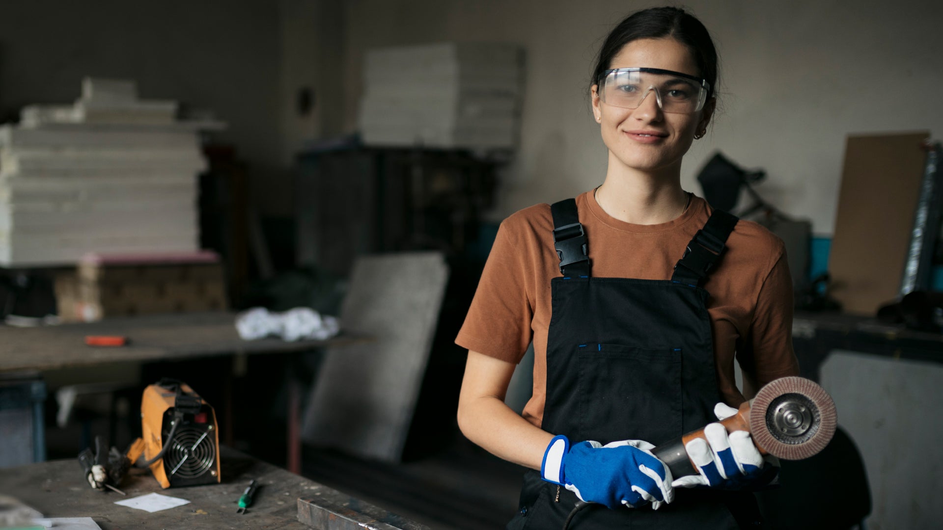 Glass articst holds grinder and wears safety goggles.