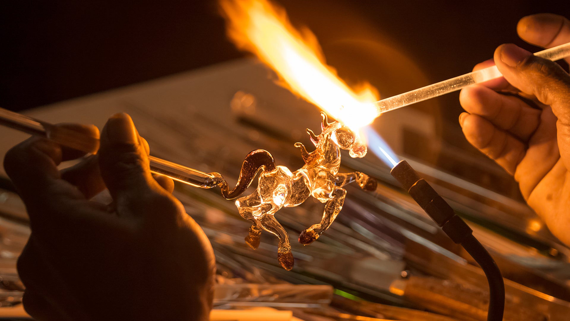 Closeup shot of a glass horse figurine being created using a blowtorch as a lampworking technique.
