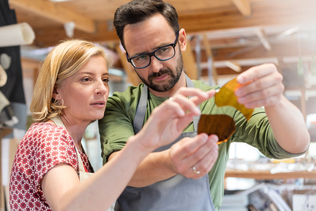 two glassworkers examining workpiece in studio