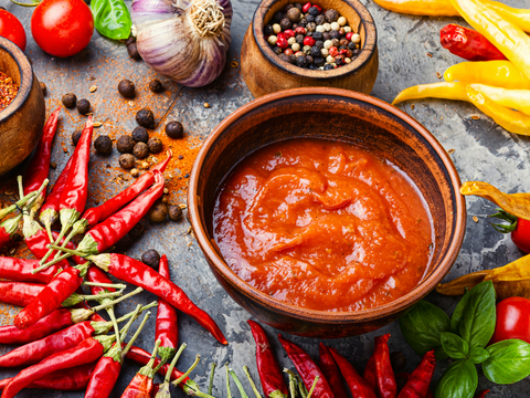 bowl of hot sauce surrounded by peppers and spices