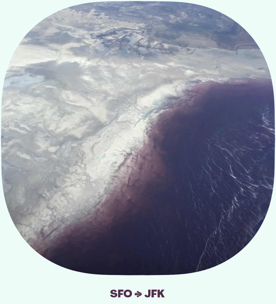 SFO>JFK: A view of a desert landscape and a purple colored lake
