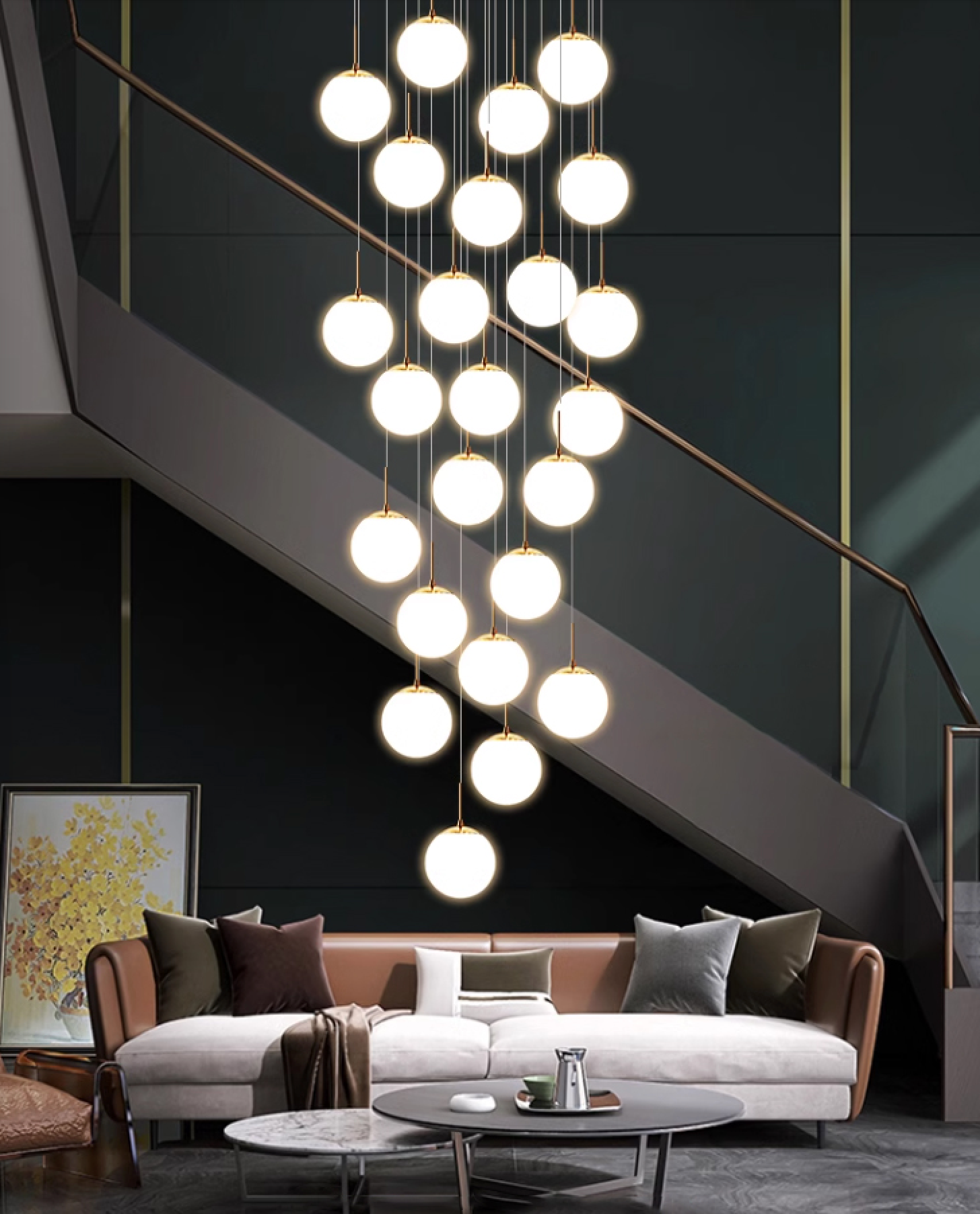 A contemporary living room with a striking chandelier of glowing spherical pendant lights hanging from the ceiling in a cascading arrangement. The lights, suspended by sleek gold stems, form an elegant display in front of a dark staircase with clean, angular lines. Below, a spacious L-shaped sofa in neutral tones with brown, white, and green cushions adds a cozy touch. The modern coffee table in front of the sofa complements the minimalist design, and a framed artwork featuring yellow flowers rests against the dark wall, providing a pop of color to the sophisticated setting.