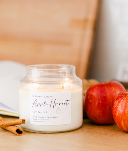 apple harvest candle with apples and cinnamon sticks on a kitchen counter