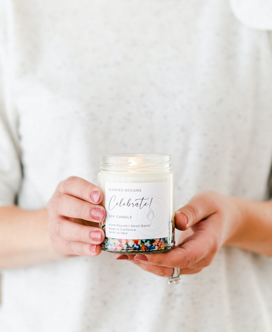 woman holding birthday cake candle with rainbow sprinkles 