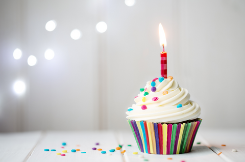 birthday cupcake with sprinkles and a lit birthday candle 