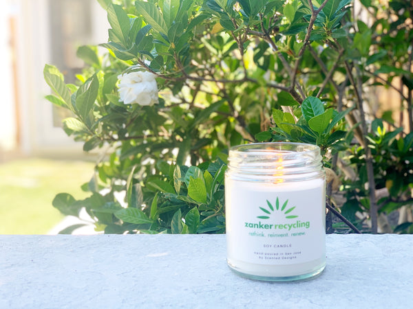 custom logo candle for recycling company in front of gardenia plant 