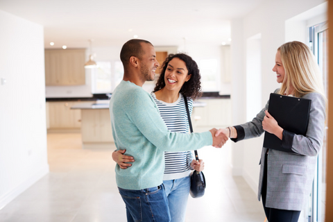 realtor with clients shaking hands in new home