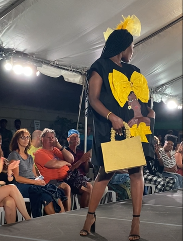 woman in black dress with a bow on the front holding yellow handbag