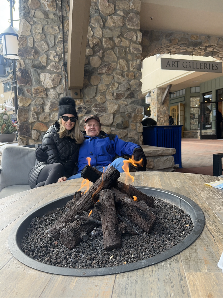 Erin and her husband at a fire pit in Vail