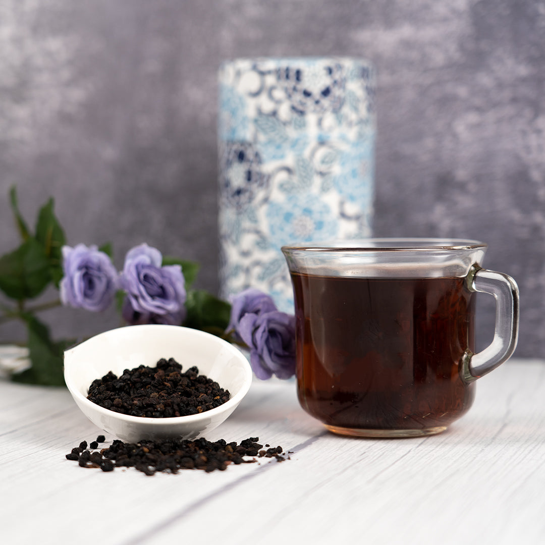 Elderberry tea in a glass mug with a small white dish filled with elderberries