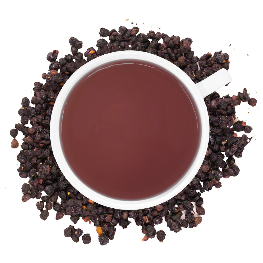 Elderberry tea in a white cup surrounded by dried elderberries