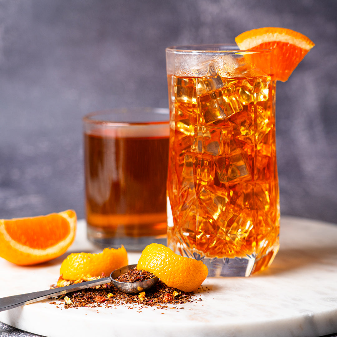 Organic Blood Orange Rooibos Iced in a glass cup with blood orange wedges and blood orange rooibos tea in a spoon