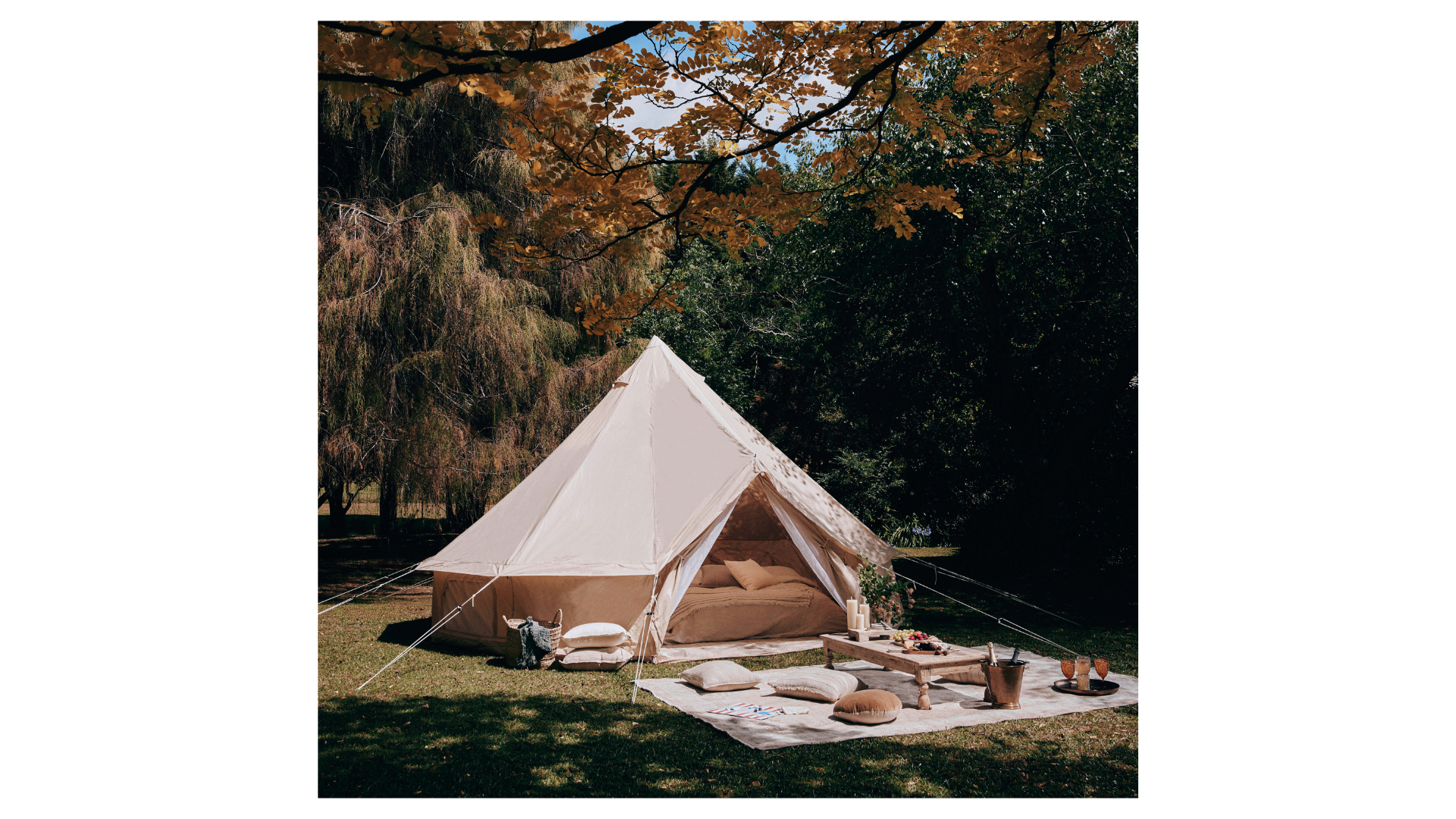 Glamping setup with canvas bell tent with outdoor rug and coffee table