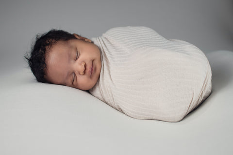 sleeping baby in a white swaddle