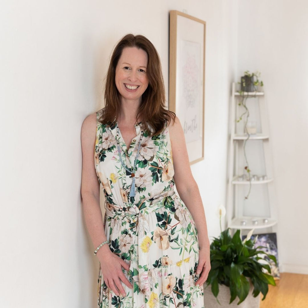 Carol Fung founder of Seeds of Wonder wearing floral dress leaning on wall