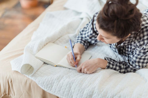 Woman journalliung while lying on bed