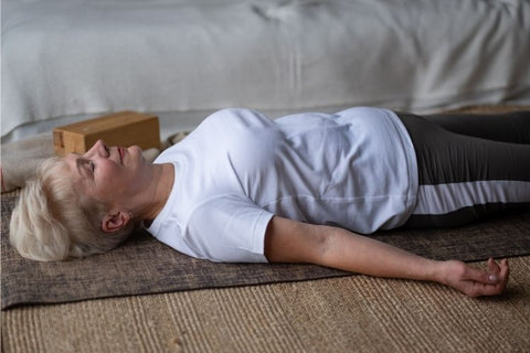 Woman lying on floor in corpse pose