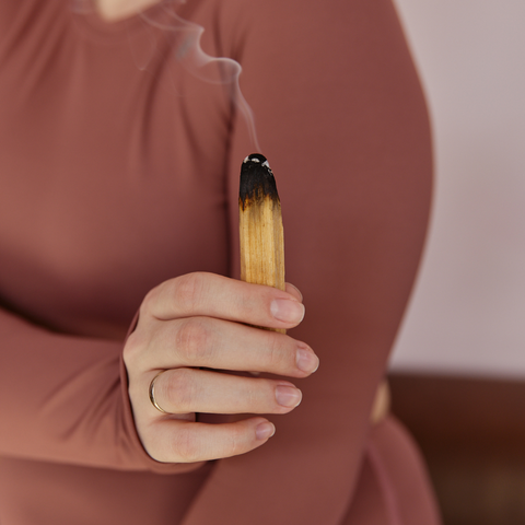 Woman using Palo Santo stick to smudge