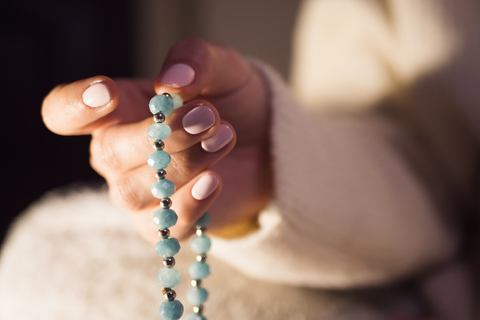 Women counting beads on a mala in her hand 