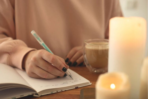Woman journaling in notebook with candles