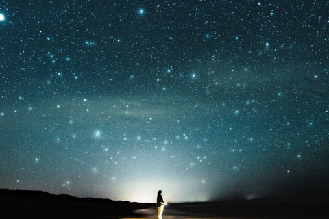 Person looking up into vast starry night sky