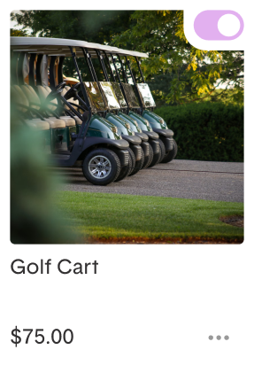 Multiple golf carts parked in a row on a paved path.