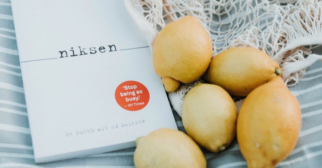Boek Niksen van Olga Mecking ligt op frisblauw picknickkleed met citroenen omgeven