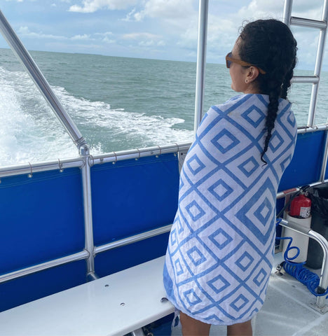 Woman on a boat using a blue white Turkish towel as a shawl