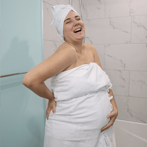 Pregnant woman wearing a Turkish towel on her body and in her hair after the shower