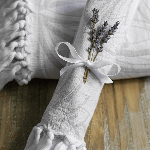 Grey and white Turkish towel set with a white bow and lavender on a wooden surface