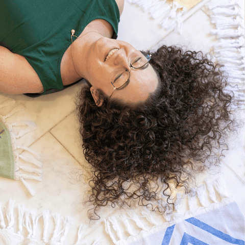 Smiling person with long curly hair surrounded my Turkish towels