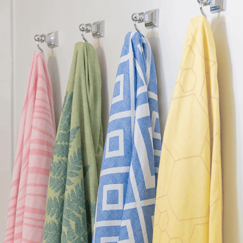 Four Pomp & Sass towels, honeycomb, red striped, green leaf and blue diamond designs.