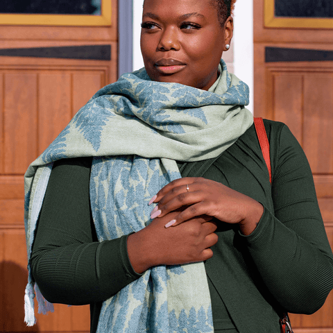 A black woman wearing green uses a green Turkish towel as a scarf.
