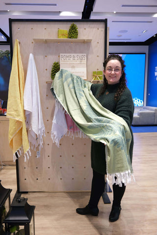 Nikky Starrett founder of Pomp & Sass hold the green Fern Body Towel made with pure Turkish cotton in front of their booth at the RBC eXperience Market located in the Sherway Garden Mall 2022