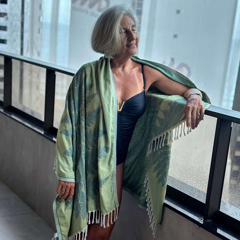 Elderly woman in a black bathing suite wearing a green fern Turkish towel over her shoulders