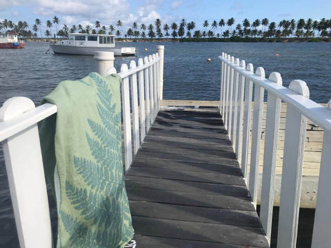 Green fern Turkish towel hand drying by the water on a white fence