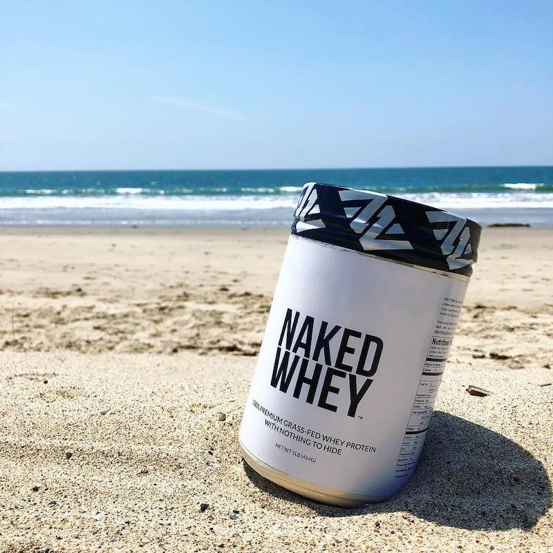 Tub of Unflavored Naked Whey in the sand in front of the sea