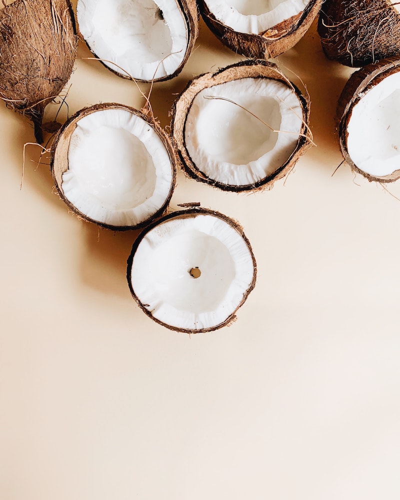 Pile of cut open coconuts in front of an off-white background