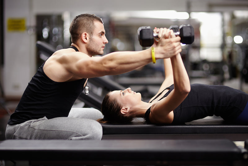 personal trainer helping woman in the gym
