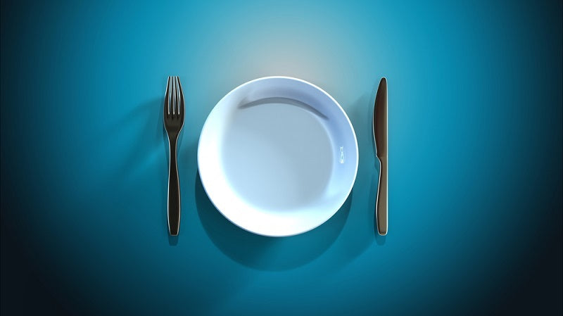 Empty plate with a knife and fork against a blue table