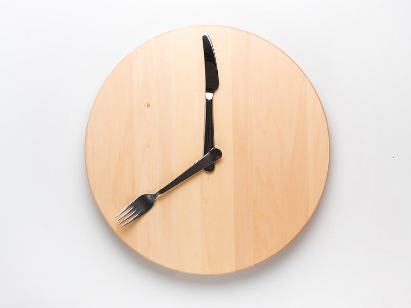 Knife and fork on a wooden plate forming a clock