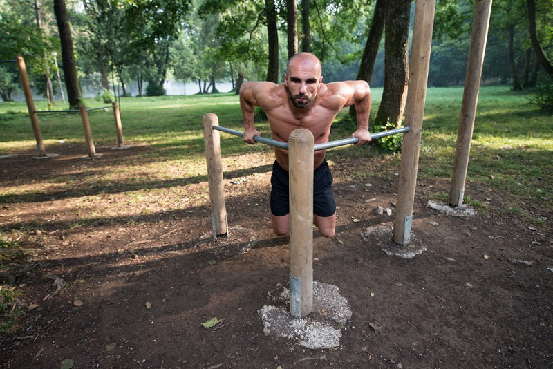 Young athlete doing dips in an outdoor gym