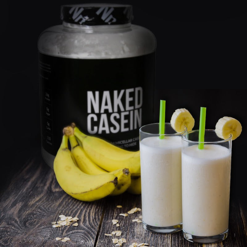 Tub of Naked Casein in the background behind two protein shakes and a bunch of bananas 